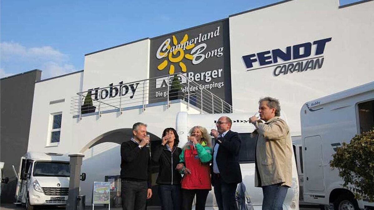 Menschen trinken Sekt vor dem Camperland Bong Gebäude
